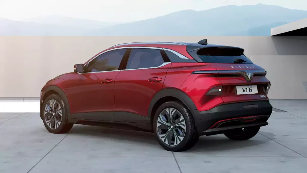 A red VinFast VF 6 electric SUV is seen from the rear three-quarter view outdoors.
